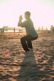 Photo d’un homme fermant ses mains et fléchissant ses jambes sur le sable. Il fait un exercice de respiration. Illustration du billet : Bonnes résolutions : et pourquoi donc ?