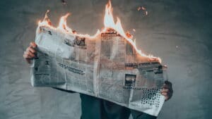 Illustration de l’émission SCOOP n°4, qui s’intitule : La vie devant nous. Il s’agit de la photo d’une personne cacher derrière le journal qu’elle lit. Le journal est en train de brûler par le haut.