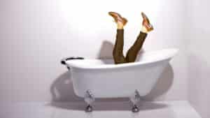 Une personne tombe dans une baignoire. On ne voit plus que ses jambes. L’illustration représente les annonces renversantes et inédites du podcast Méta de Choc.