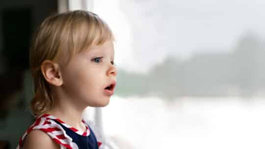 Une enfant regarde par la fenêtre, d’un air surpris et curieux. Illustration de l’émission STREAM intitulée : Enfant de la spiritualité New Age, du podcast Méta de Choc.